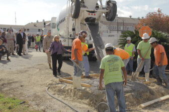 U.S. Sen. Mary Landrieu, in purple blouse, jokes with construction workers after cement spills out of wood frame. 