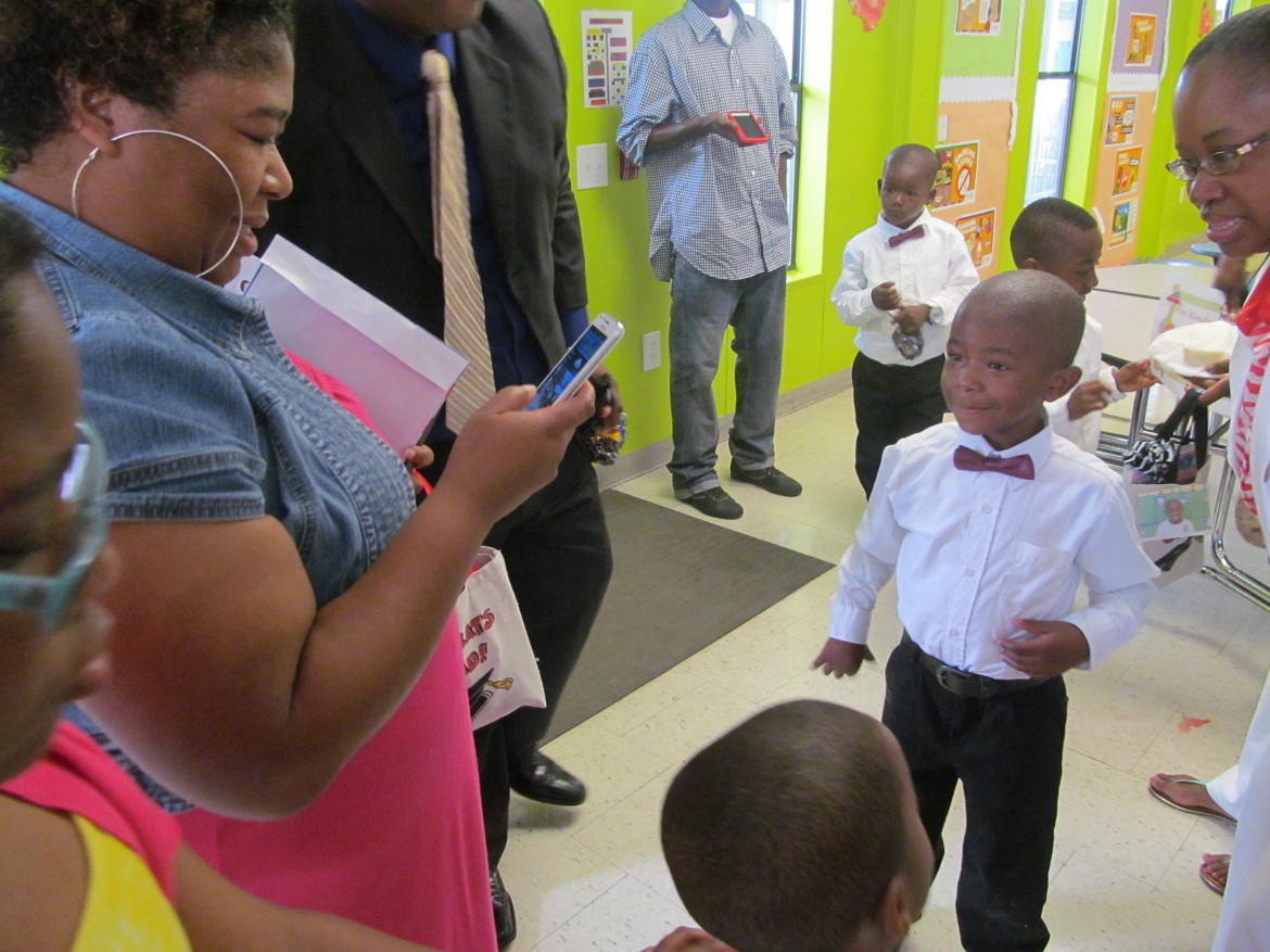 Malaika Amedee, left, takes a photo of her son Mason Garner as he graduates from kindergarten at Benjamin Mays Preparatory School on Wednesday. The school's last day was Thursday, and it will not reopen next year due to poor performance.