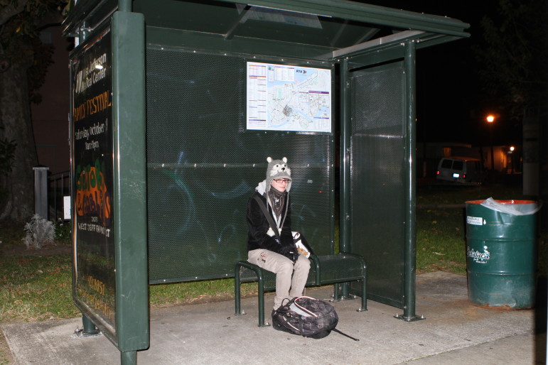Amelia Slep-Patterson waits for the bus in Algiers at the start of her long trip to school. Between the dark bus stop and the early-morning walk down Canal, she said she has to on guard.