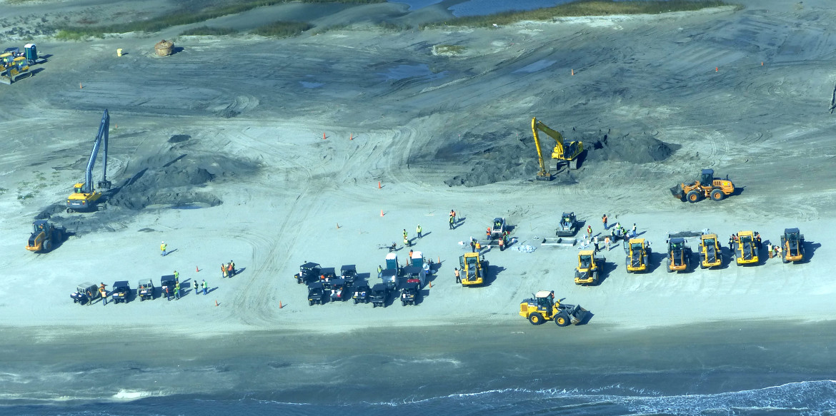 Heavy equipment digs into Fourchon Beach searching for more of the massive oil mats left  by the Deepwater Horizon disaster in 2010.