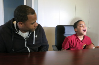 Third-grader Desean Denis shows the gap after his front two teeth were knocked out by a car at his bus stop. His father Torri Denis, left, said the boy also cut his tongue, hurt his head and was bruised on his arms and legs.