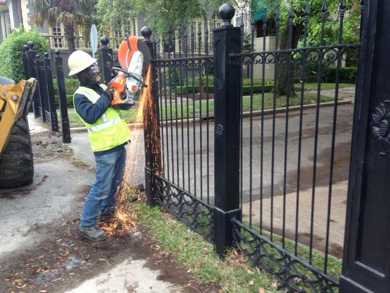 A worker cuts through the Newcomb Boulevard fence Tuesday morning.