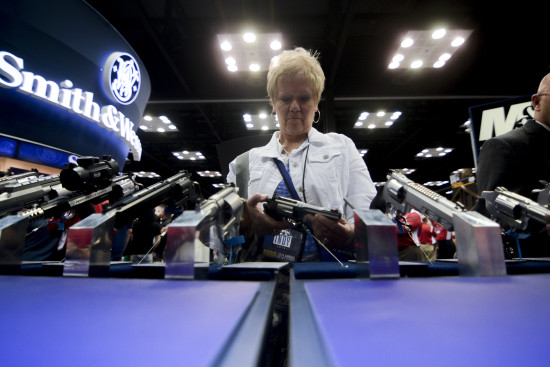 A woman holds a revolver in the exhibit hall at the NRA’s annual convention in Indianapolis.