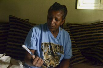 Sheila Whitmore, holding a picture of her brother Kenny, says she can barely see him through the partition when he is brought shackled into the visitor's room. 