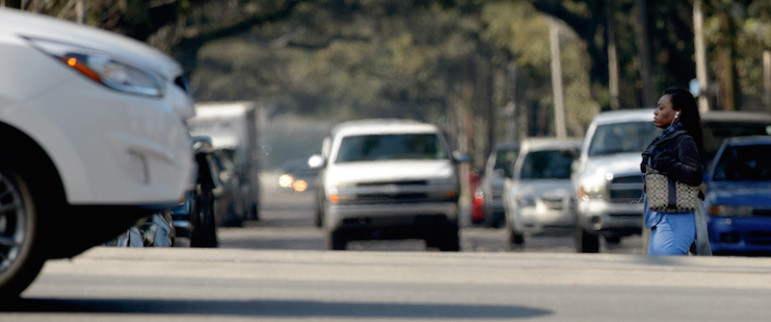 The evidence of subsidence, as well as building streets to accommodate underground canals, can be seen on roller-coaster streets and their often uneven elevations. Here a woman crossing Jefferson Davis Parkway at Canal Street is partially hidden because of the elevation differential between the two streets.