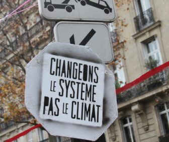 Activists in Paris rallied to a slogan urging the world to change the system, not the climate. The red ribbon symbolized a line negotiators were urged not to cross.
