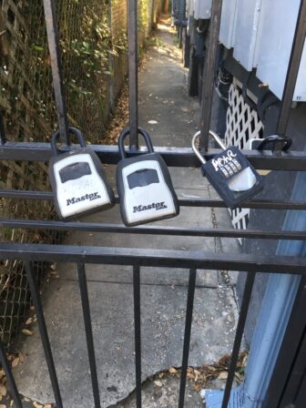 Multiple lockboxes on an alleyway gate are often a sign of short-term rental activity.