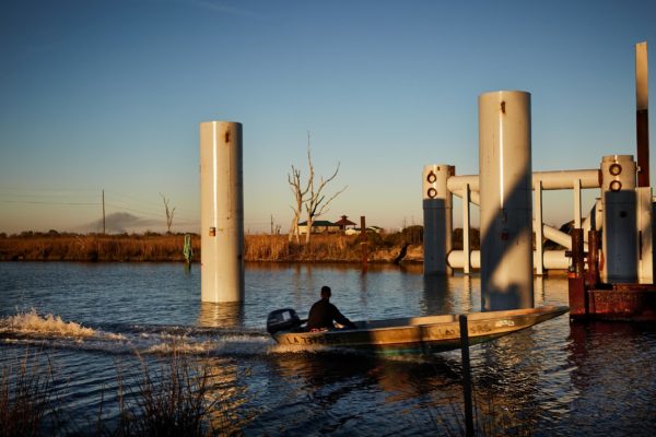 A boater passes a floodgate under construction in Bayou Pointe-aux-Chenes.