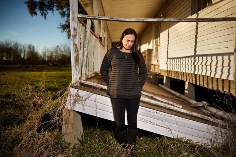 Christine Verdin stands in front of her wrecked childhood home next to the Pointe-au-Chien Indian Tribe’s community center. The home was damaged by Hurricane Rita in 2005.