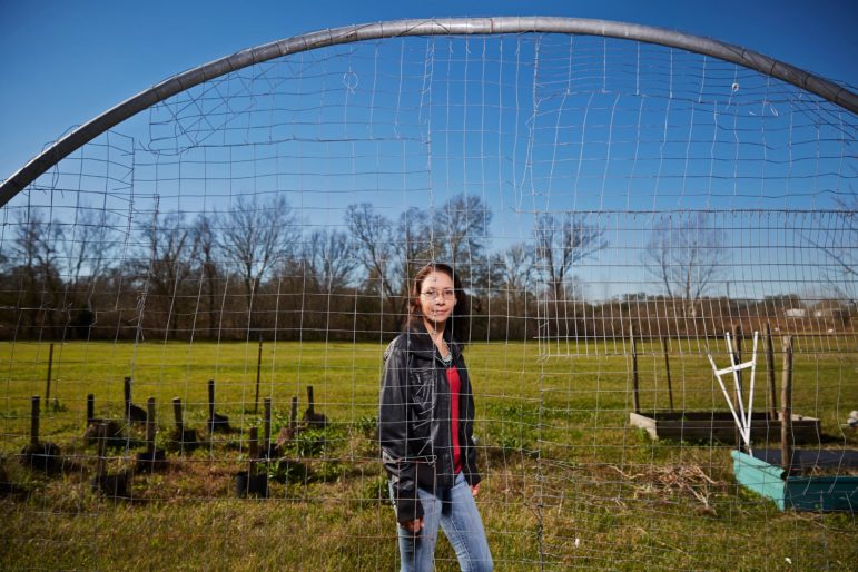 Chief Shirell Parfait-Dardar, of the Grand Caillou/Dulac Band of Biloxi-Chitimacha-Choctaw Indians, stands behind the trellis for her green beans, made of old trampoline parts.