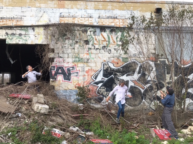 The author (middle) and colleagues clear away trash and underbrush to get a better look at the mural. 